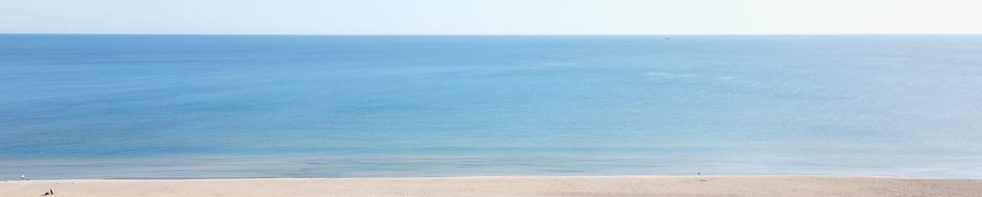 Luftaufnahme der Ostseeküste: breiter Sandstrand mit Strandkörben und das offene Meer